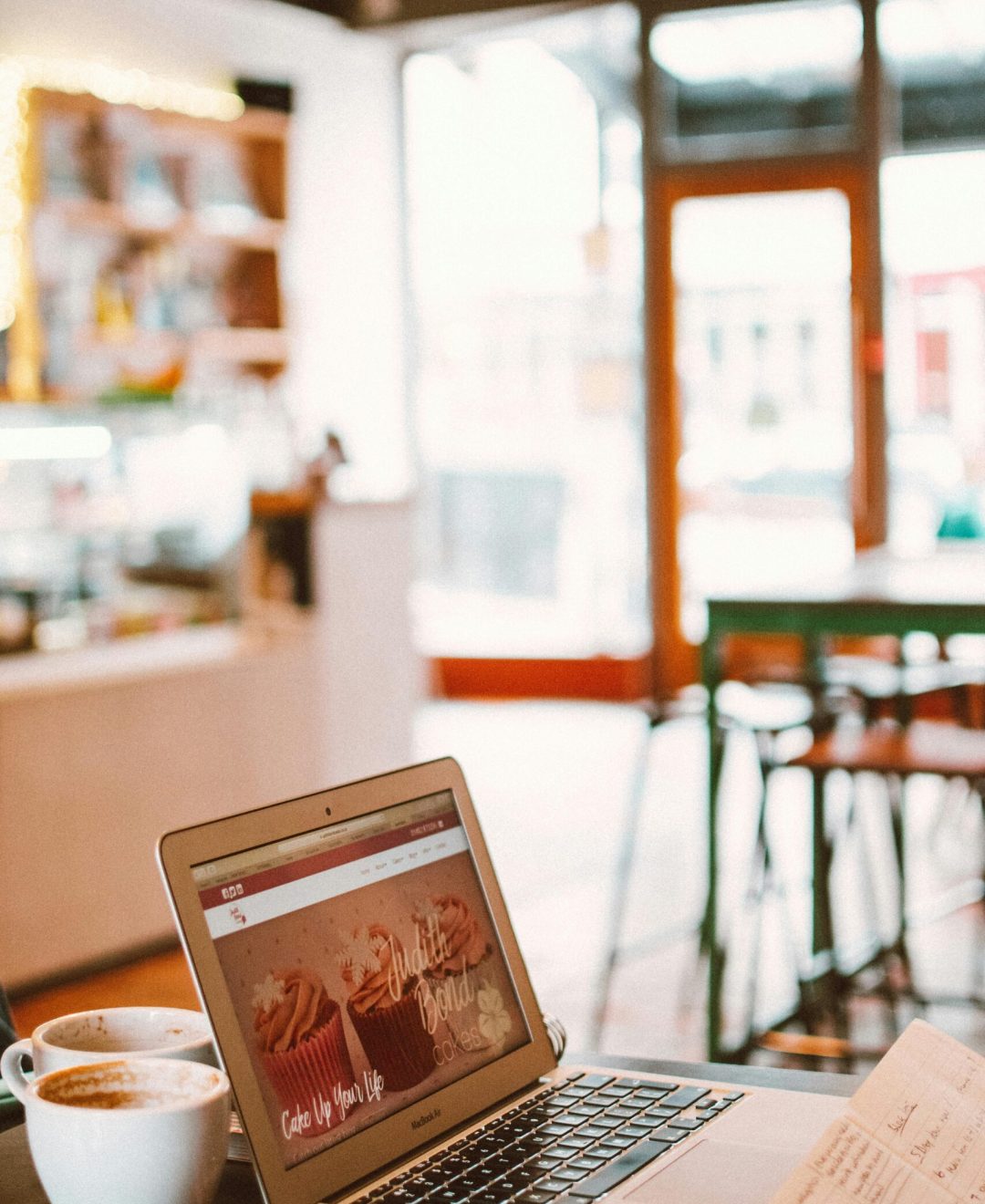 A cozy café setting with a laptop, coffee, and notebook, perfect for working or blogging.